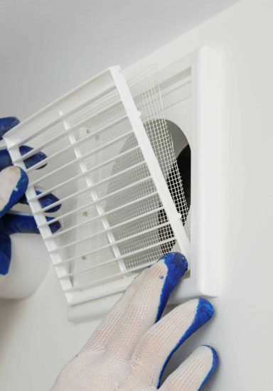 Worker installs ventilation grille on the wall.